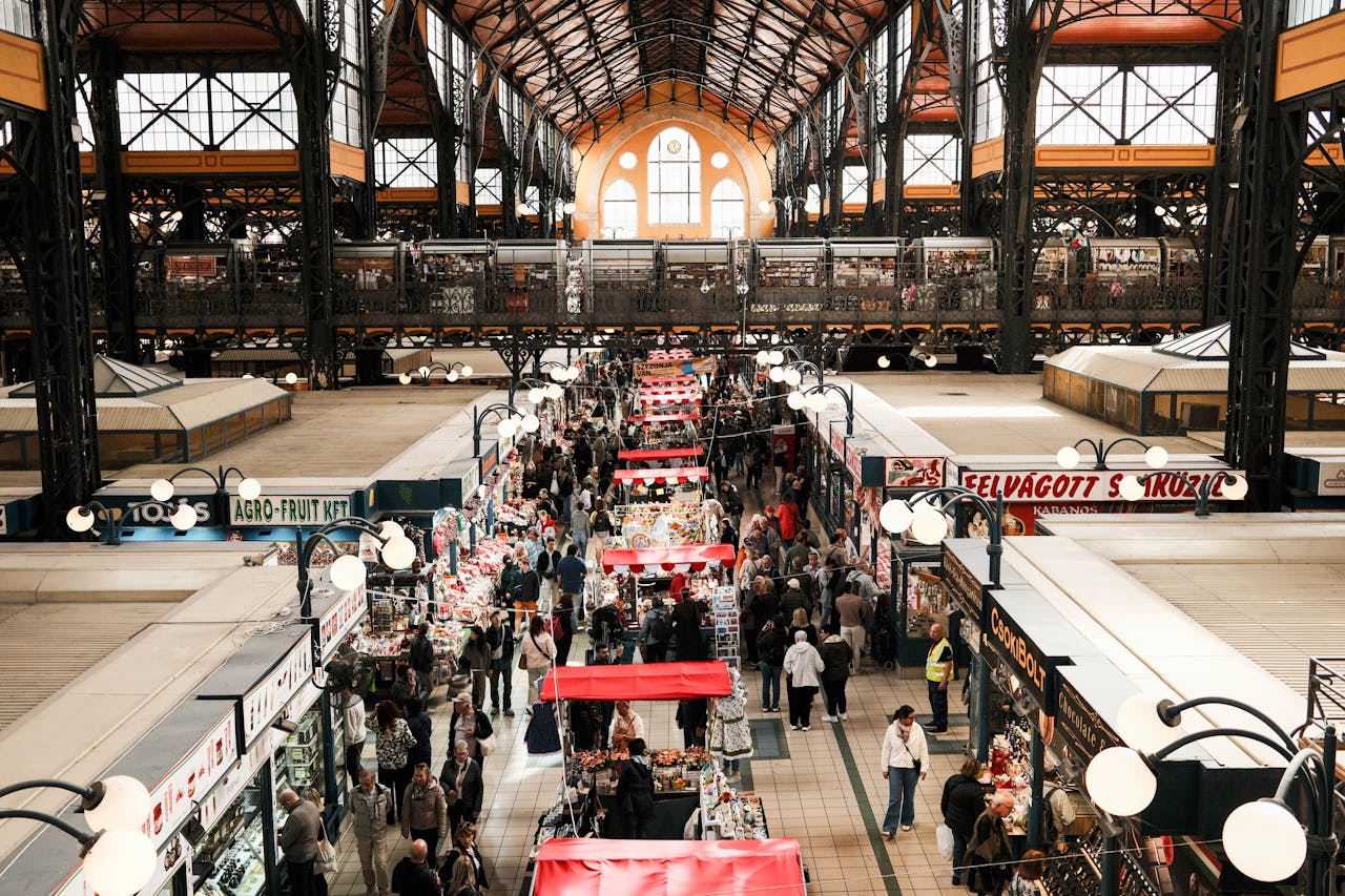 Explore the vibrant Budapest Central Market Hall filled with shoppers and vendors captured from above.